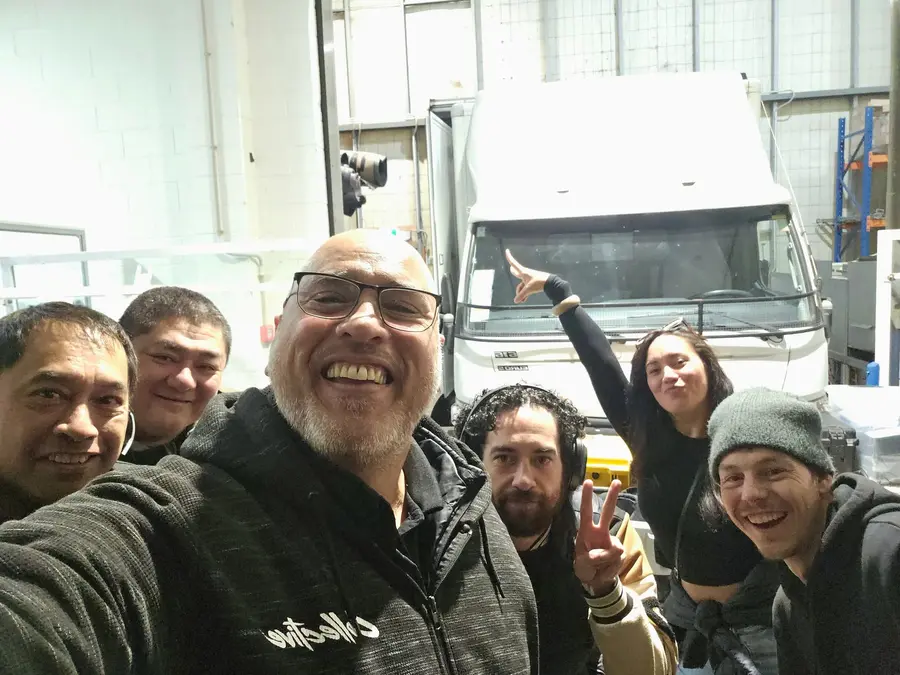 Smiling Manaia Go crew in front of the OB truck in a warehouse
