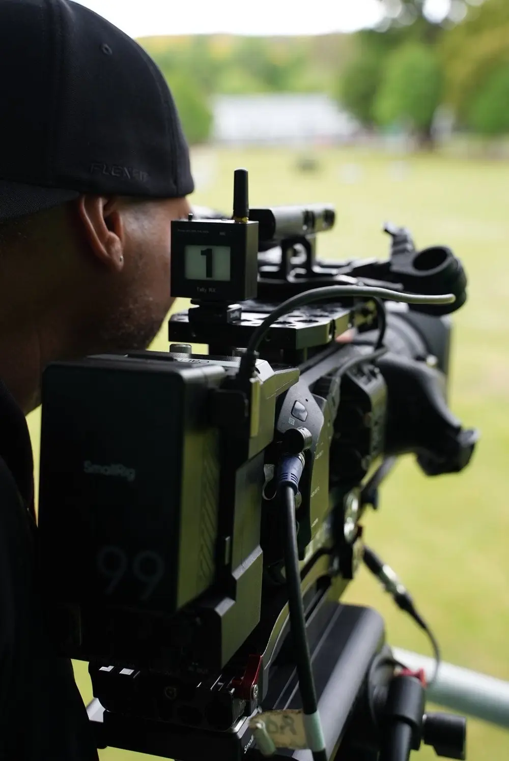 Camera operator with tally light on a broadcast camera, filming an outdoor parade